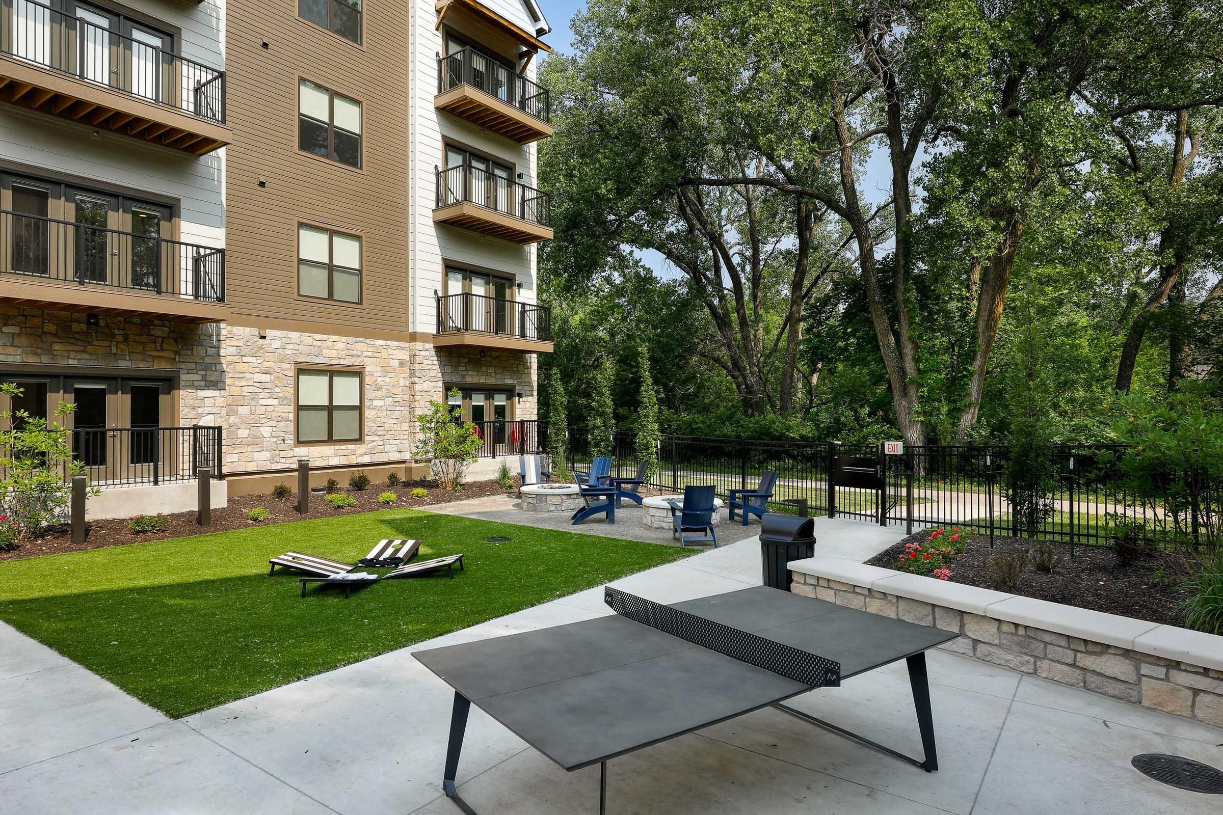 Outdoor recreational area at Wheatfield Village with seating, a fire pit, and a ping pong table.