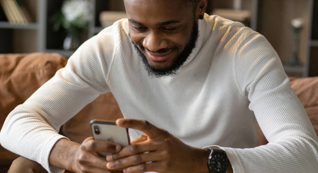 Man looking at phone in a cozy living area at Wheatfield Village.