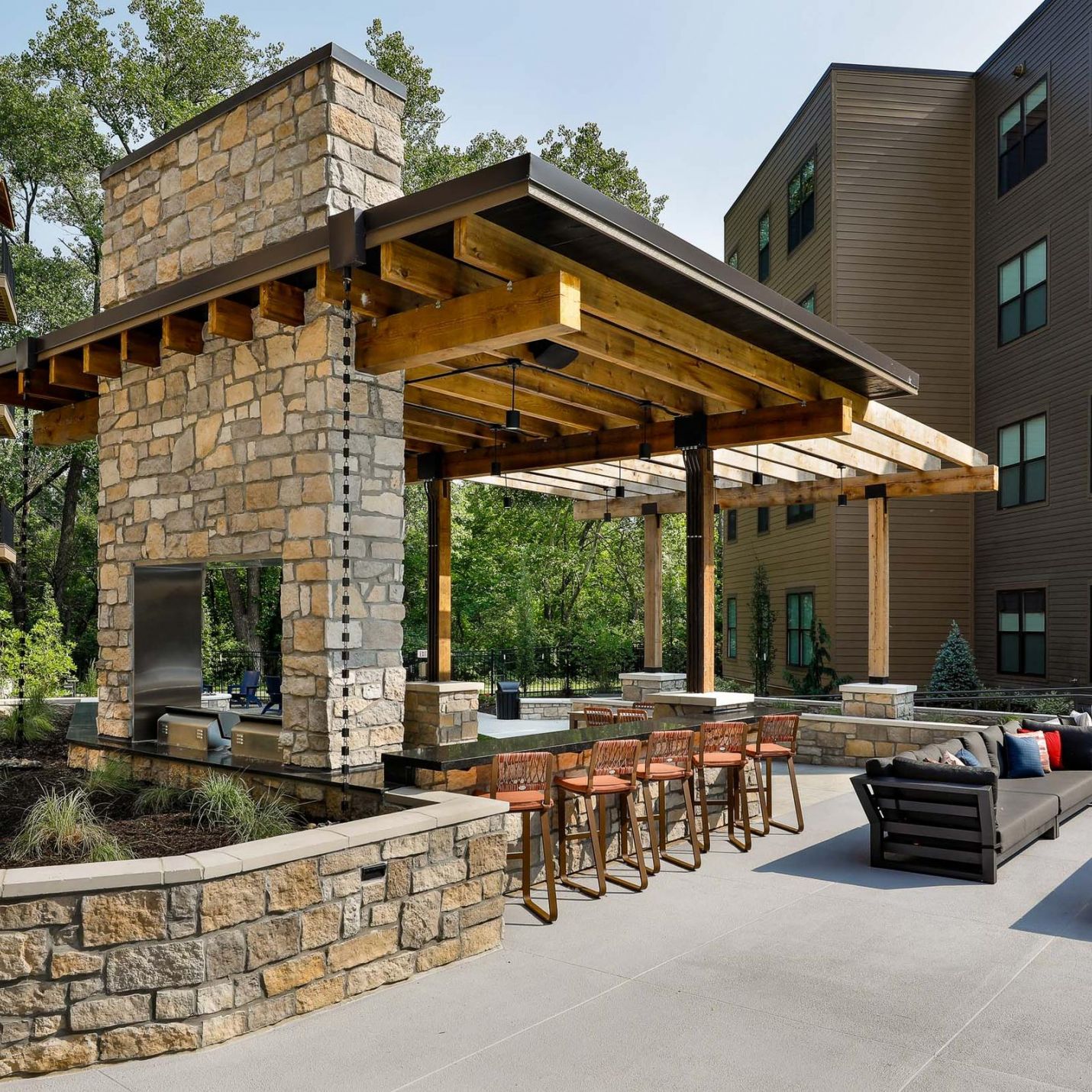 Wheatfield Village outdoor resident kitchen bar with barstool seating, and awning, and beautiful stonework details.