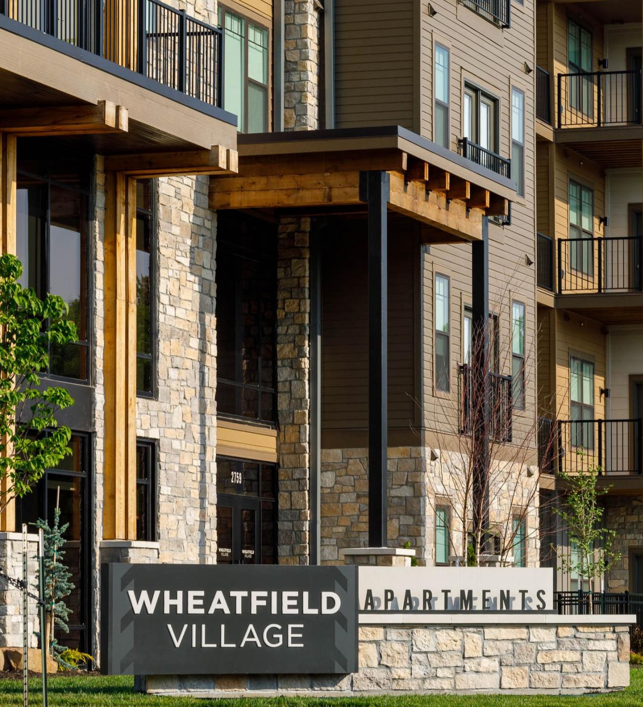 Wheatfield Village exterior view of apartments with neutral brown colors and stone accents.