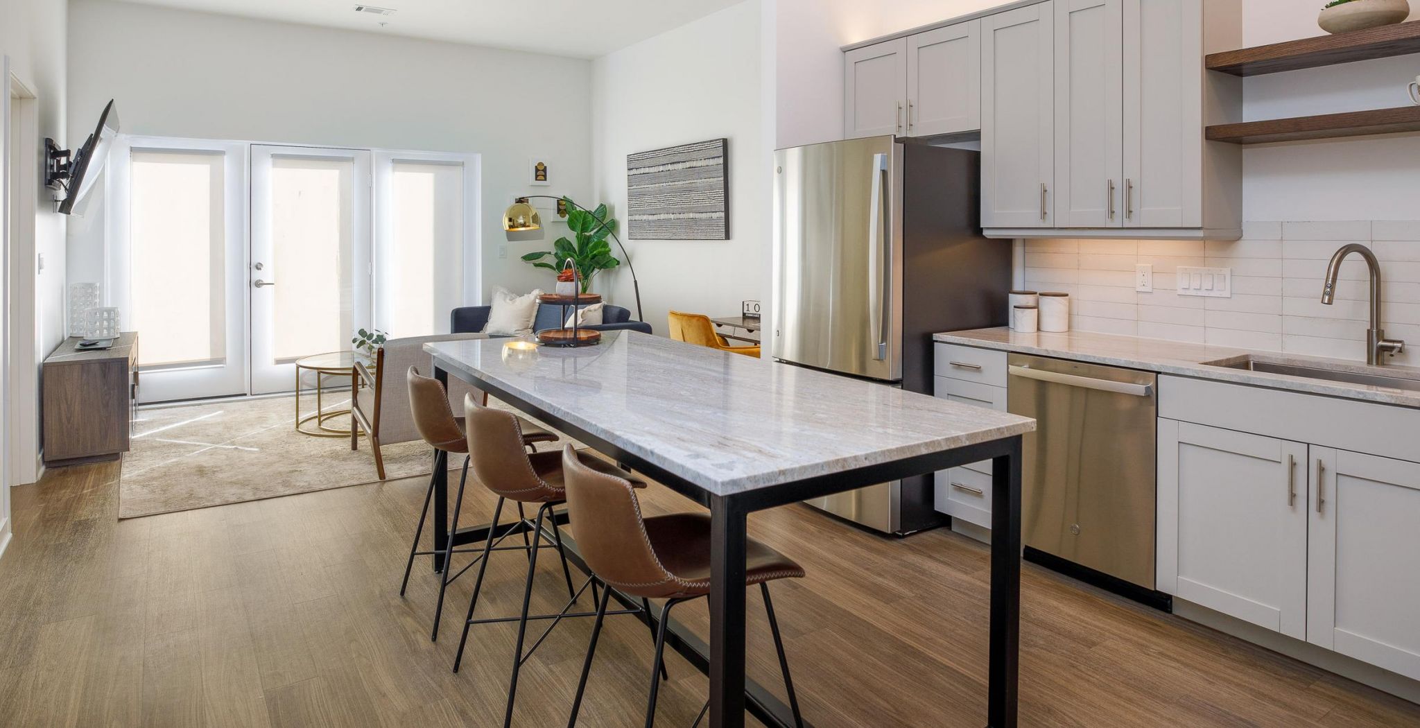 Modern kitchen in an apartment at Wheatfield Village with large island counter with seating and stainless steel appliances.