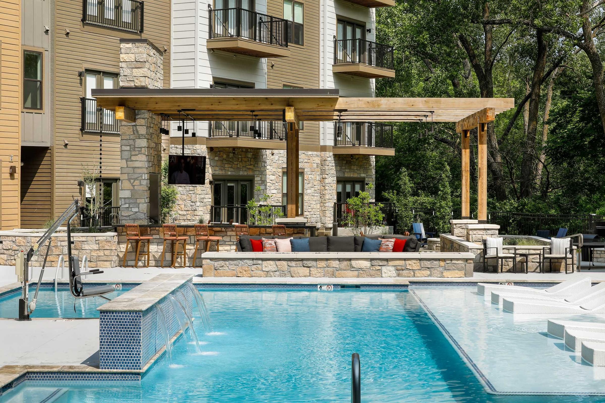 Outdoor pool and lounge area at Wheatfield Village featuring a pergola and seating.