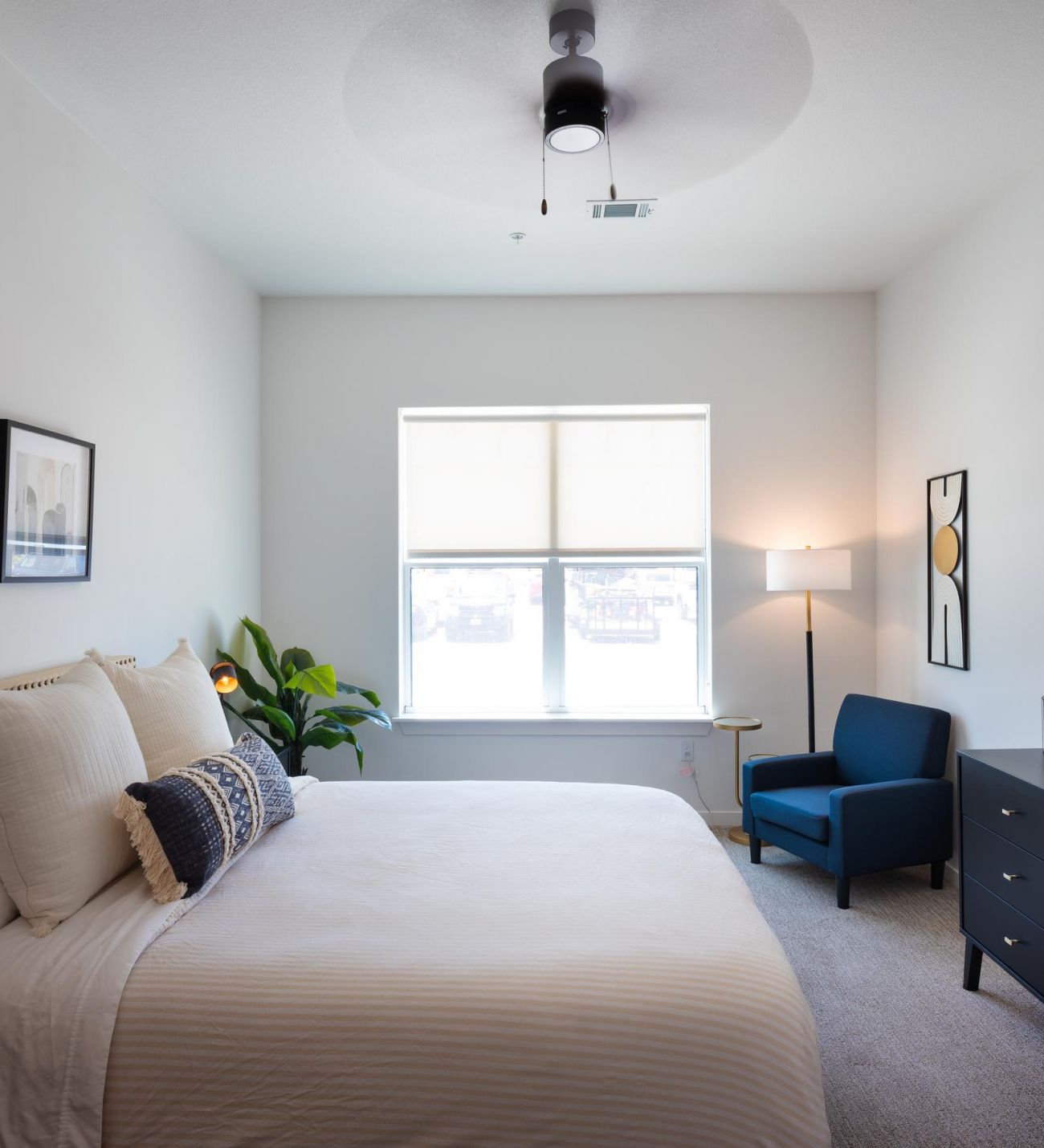 Wheatfield Village apartment bedroom with large window, fan, and new carpeting.