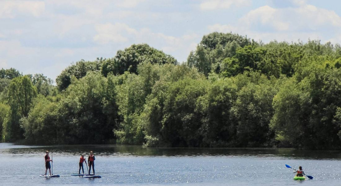 People paddleboarding and kayaking at a nearby lake to Wheatfield Village.