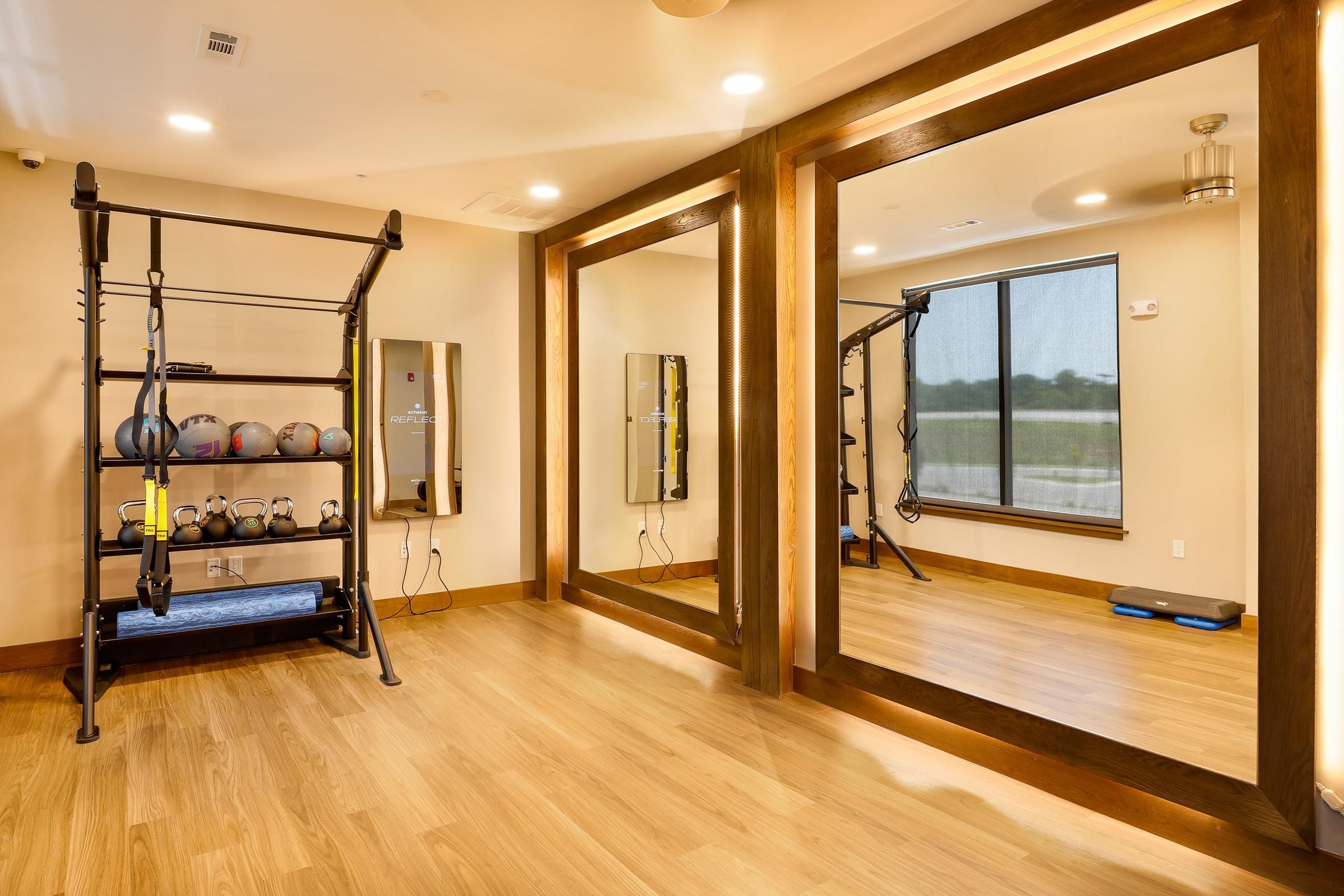 Spacious fitness room at Wheatfield Village featuring mirrors and various workout equipment.