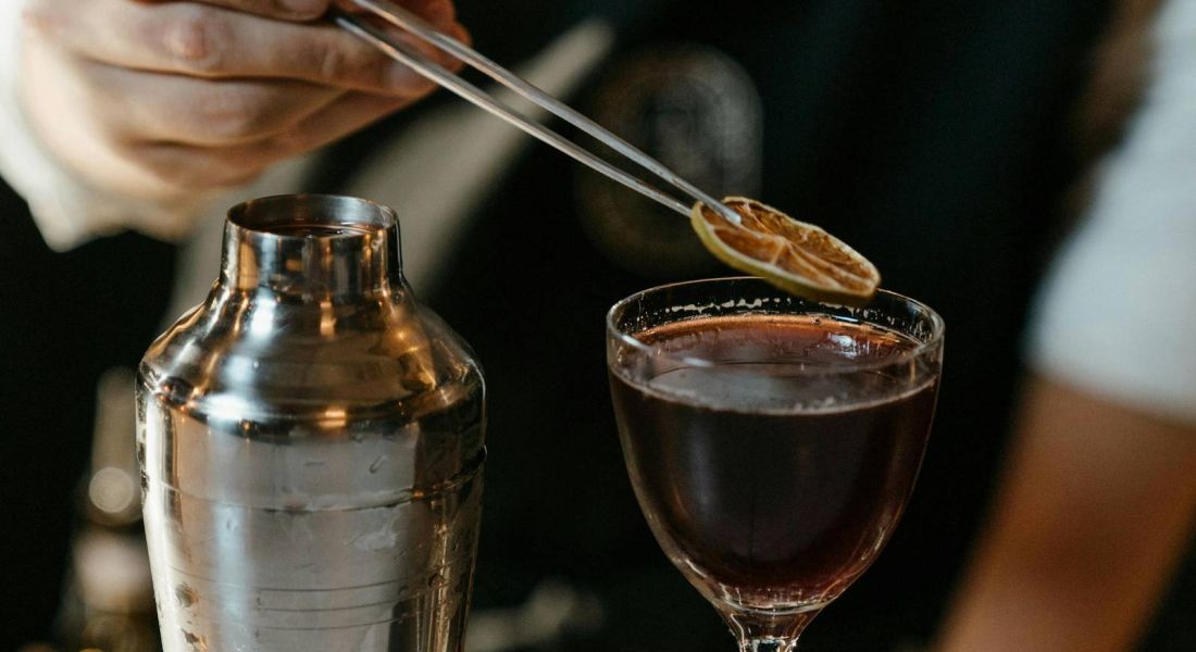 Bartender preparing a crafted cocktail at a bar near Wheatfield Village.
