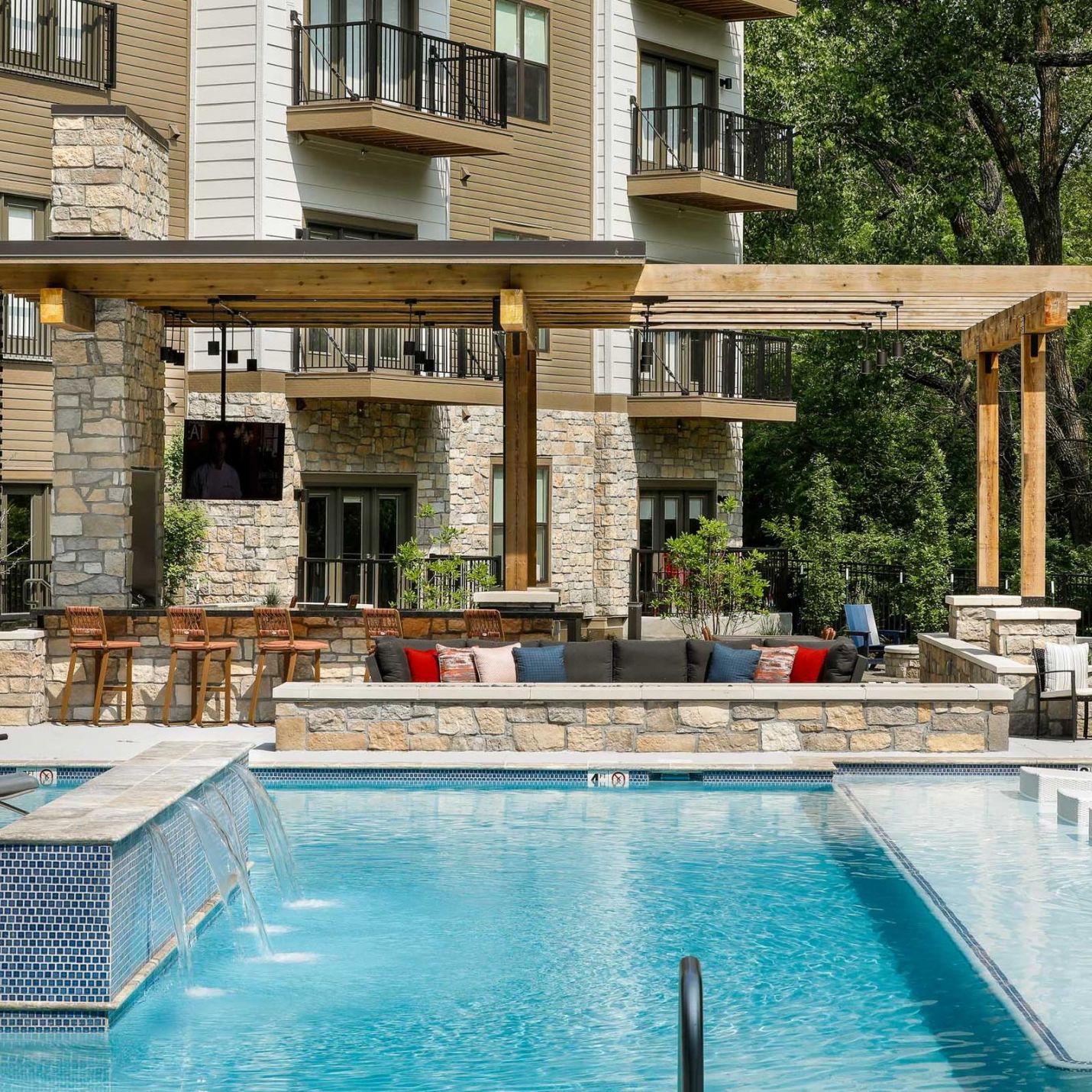 Outdoor pool and lounge area at Wheatfield Village featuring a pergola and seating.