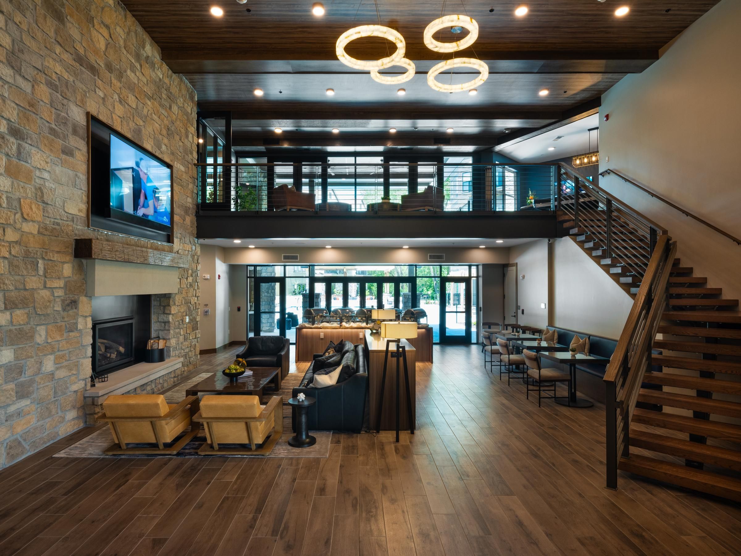 Grand lounge area at Wheatfield Village featuring a stone fireplace, comfortable seating, and a loft-style upper level.